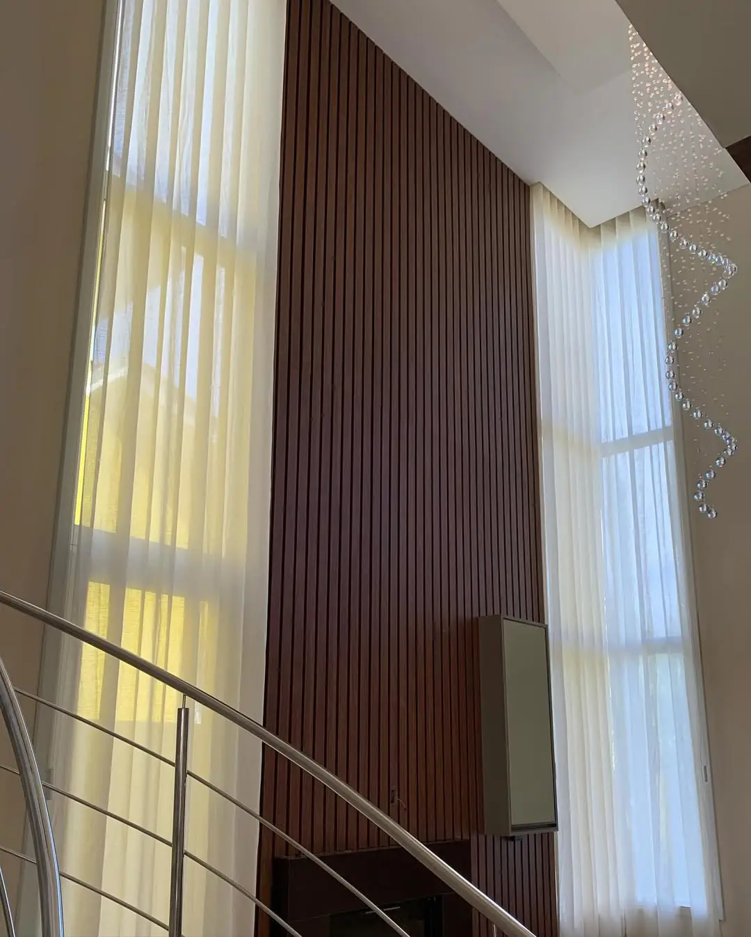 Pé-direito duplo com voil ao lado de painel ripado
