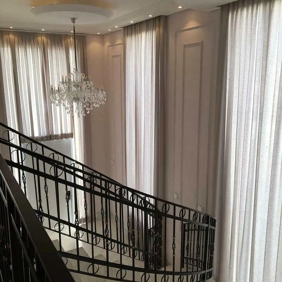 Pé-direito duplo com cortinas de voil ao lado da escada