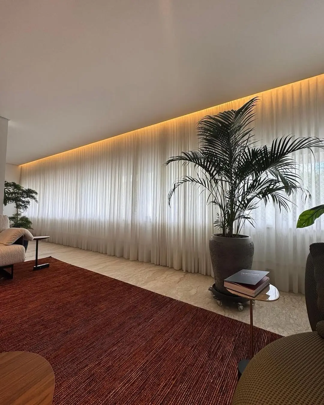 Sala ampla com cortina de voil do teto ao chão e iluminação embutida